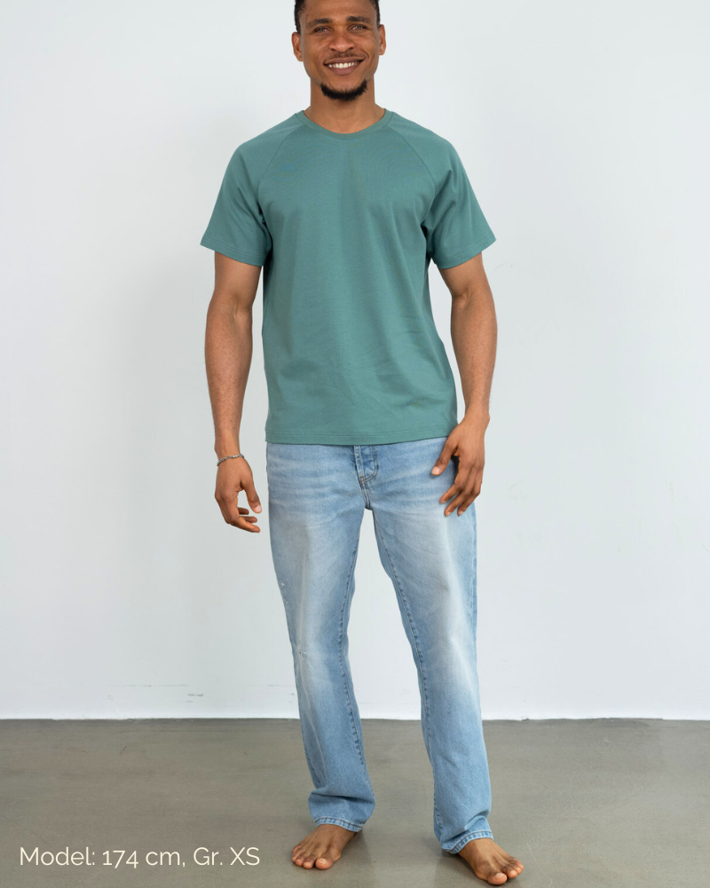 Ein Mann trägt eine Jeans und ein grünes Raglan Shirt der Marke Oktopulli