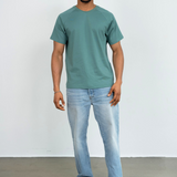 Ein Mann trägt eine Jeans und ein grünes Raglan Shirt der Marke Oktopulli