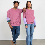  Eine Frau und ein Mann stehen beide lächelnd nebeneinander und tragen dabei den pinken Unisex Sweater von Oktopulli